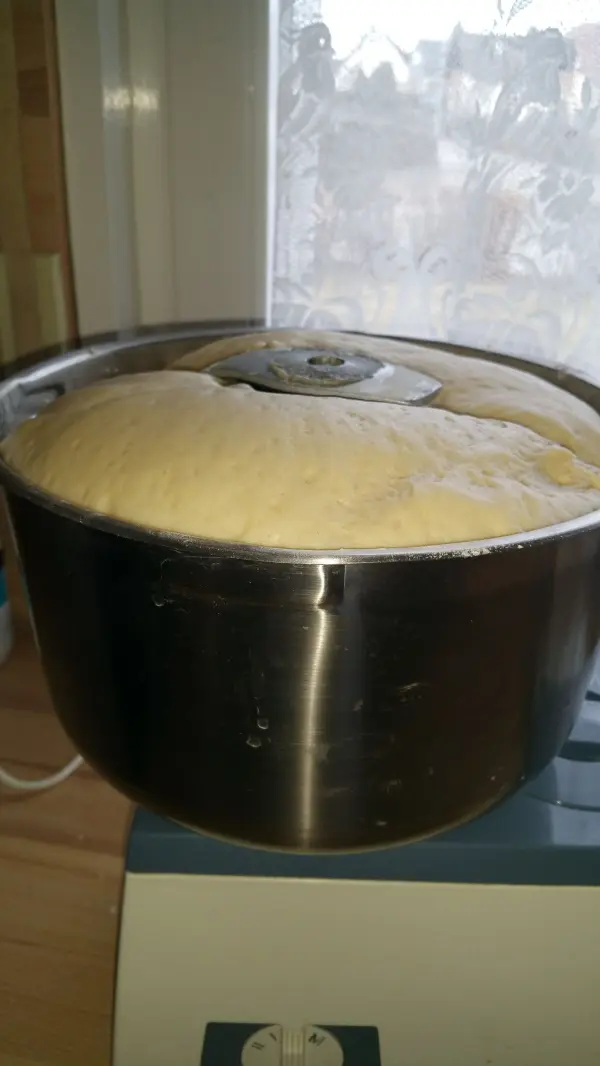 Der Teig für den saftigen Apfelkuchen mit Grießbrei und Streuseln geht in einem großen Topf neben einem Fenster auf.