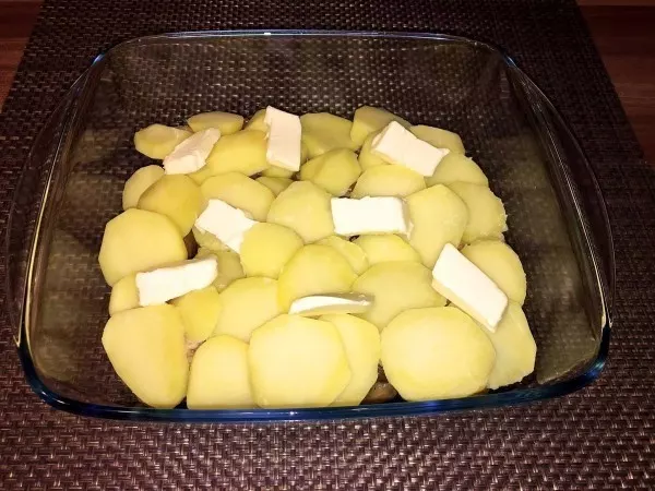 Auf das Gebratene aus der Pfanne wurden die abgekühlten Kartoffelscheiben platziert. Auf den Kartoffelscheiben habe ich in Stücke geschnittene Butterstücke verteilt.
