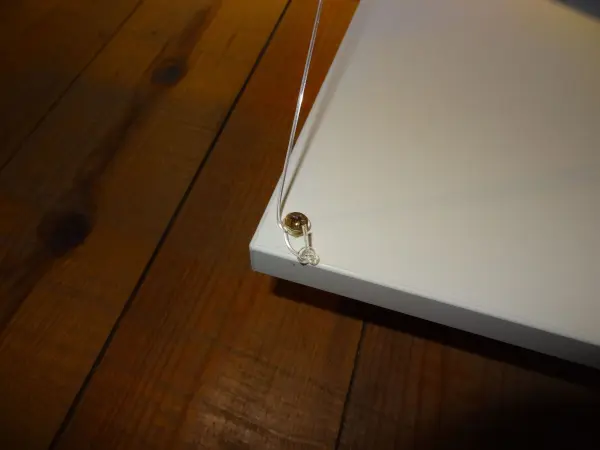 Eine Drucktür wird mit einem Kabel gesichert, um einen Schlag auf den Boden zu verhindern; sie hängt über einem Holzboden.