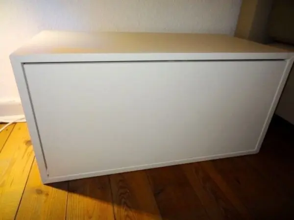 Eine weiße Nachttisch-Drucktür wird vor einem Sturz auf den Boden geschützt, um Schäden zu vermeiden, im Schlafzimmer.