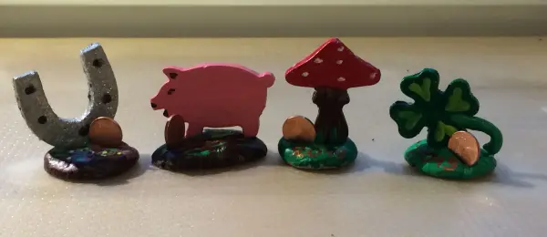 Ein Glücksbringer aus vier farbenfrohen Figuren: ein Hufeisen, ein Schwein, ein Pilz und ein Kleeblatt, alle handgefertigt.