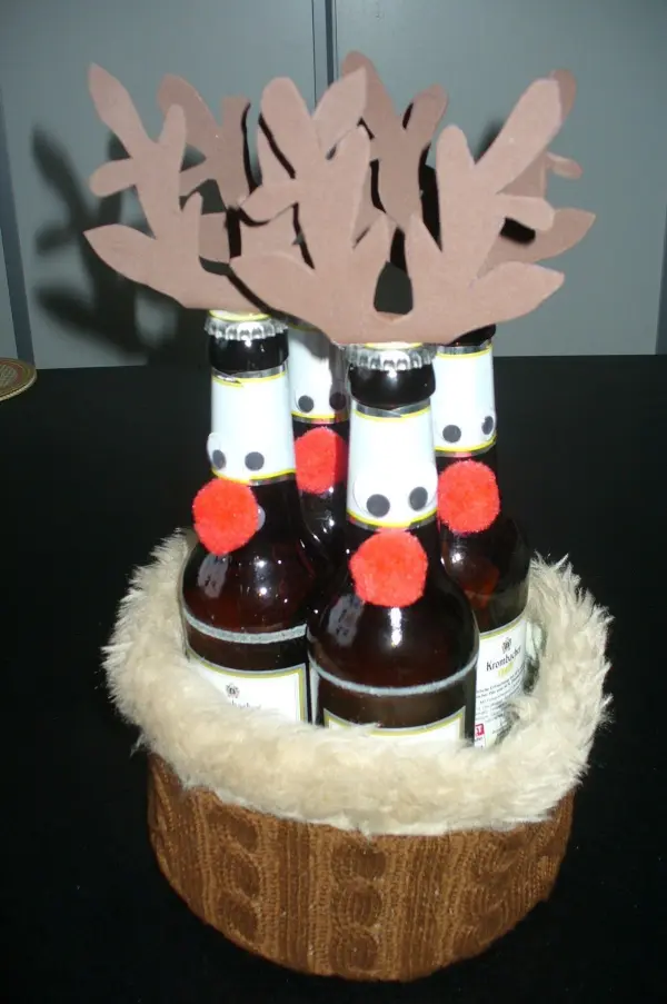 Eine Gruppe von Bierflaschen, dekoriert mit einem Geweih aus Pappe und roten Pompons, sitzt in einem geflochtenen Korb.