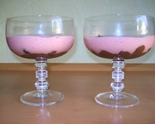 Zwei Dessertgläser zeigen eine Mousse au Chocolat mit fruchtigem Sektschaum, elegant auf einem Holztisch serviert.