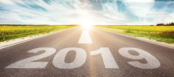Eine geradlinige Straße mit der Zahl „2019“ darauf führt in die Helligkeit einer erleuchteten Zukunft in einer ländlichen Umgebung.
