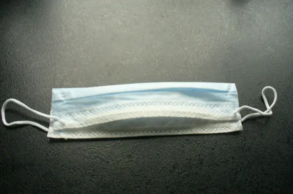 Eine medizinische Maske liegt flach auf einer dunklen Oberfläche, bereit zum Einsatz, um die Nase vor Kälte zu schützen.