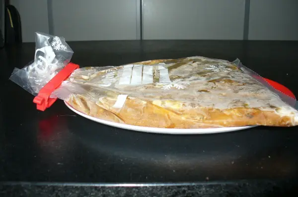 Eine gefrorene Suppe in einem Plastikbeutel liegt flach auf einem Teller, bereit zum Einfrieren in der Küche.