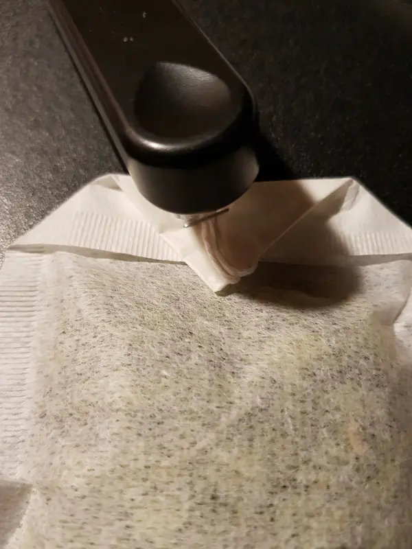 Ein hübscher Teebeutel wird mit einem schwarzen Teebeutelheber geöffnet, um frischen Tee zuzubereiten.