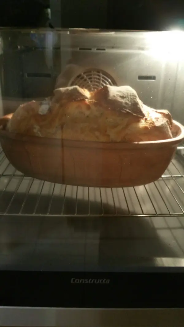 Ein golden gebackenes Joghurtbrot ruht im Römertopf, während es im Ofen leicht aufsteigt und backt.