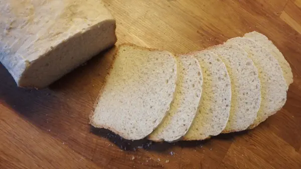 Ein frisch gebackenes Joghurtbrot liegt auf einem Holztisch, mit mehreren geschnittenen Scheiben, die appetitlich aussehen.