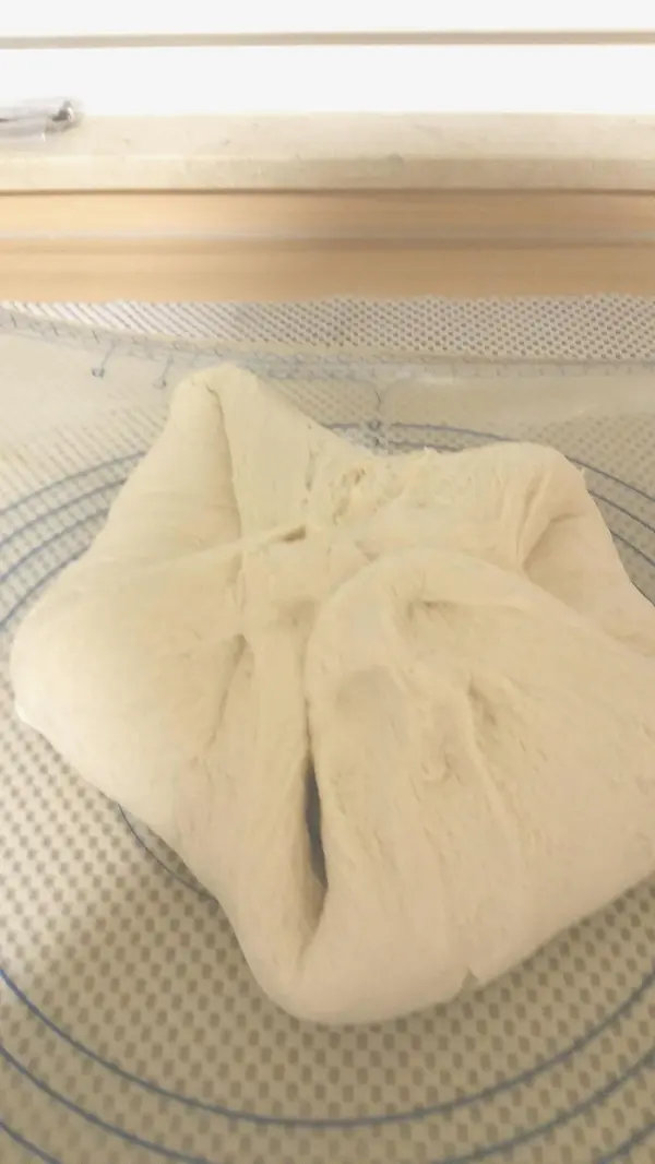 Ein weiches Joghurtbroteigstück ruht auf einer Antihaft-Arbeitsfläche, bereit zum Formen und Backen im Römertopf.
