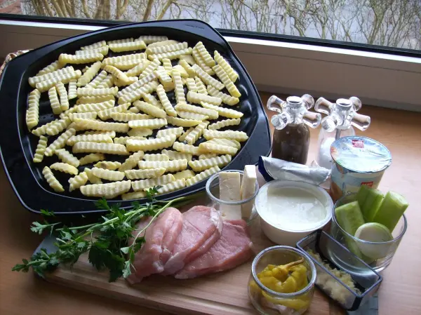 Auf einer Holzplatte liegen Schweinesteaks und frische Zutaten wie Kräuter, Joghurt und Gemüse, bereit zum Füllen nach griechischer Art.