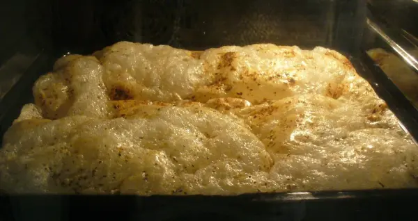 Käsechips backen im Ofen: Der Käse schmilzt und blubbert auf einem Blech, um gesunde Snacks zu kreieren.
