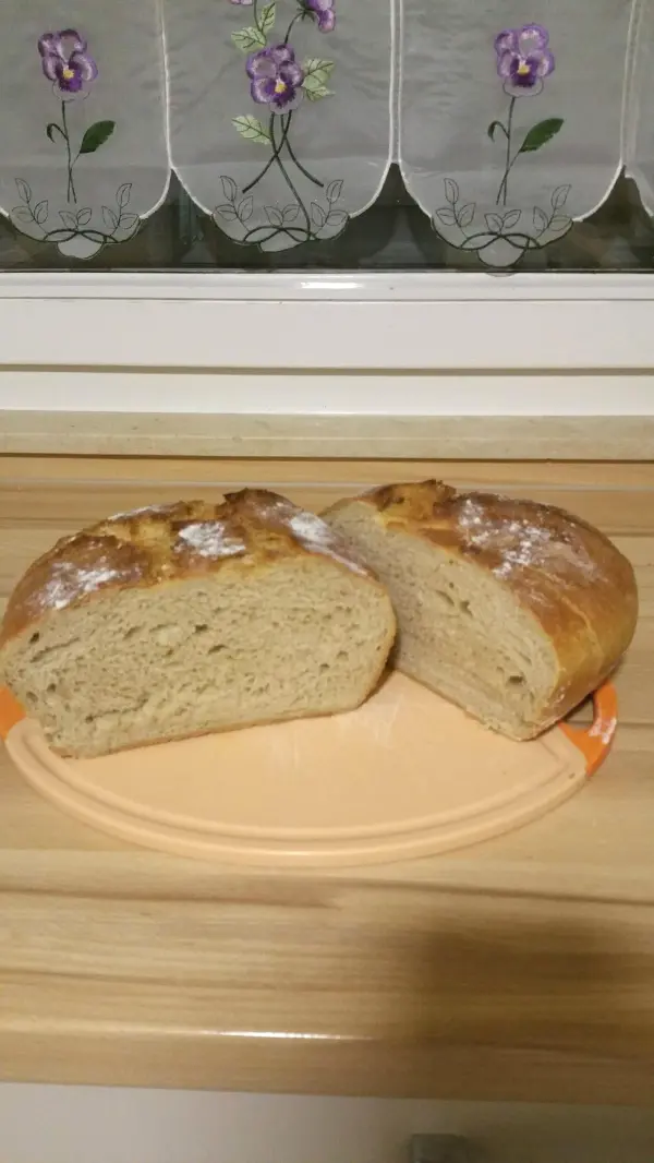 Ein frisch gebackenes Dinkel-Roggenbrot liegt auf einem Teller, es ist leicht angeschnitten und zeigt die fluffige Krume.