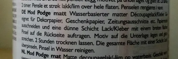 Ausgeblasene Eier im Zeitungslook liegen dekorativ auf einem Tisch, umgeben von Bastelmaterialien und Werkzeugen für kreative Projekte.