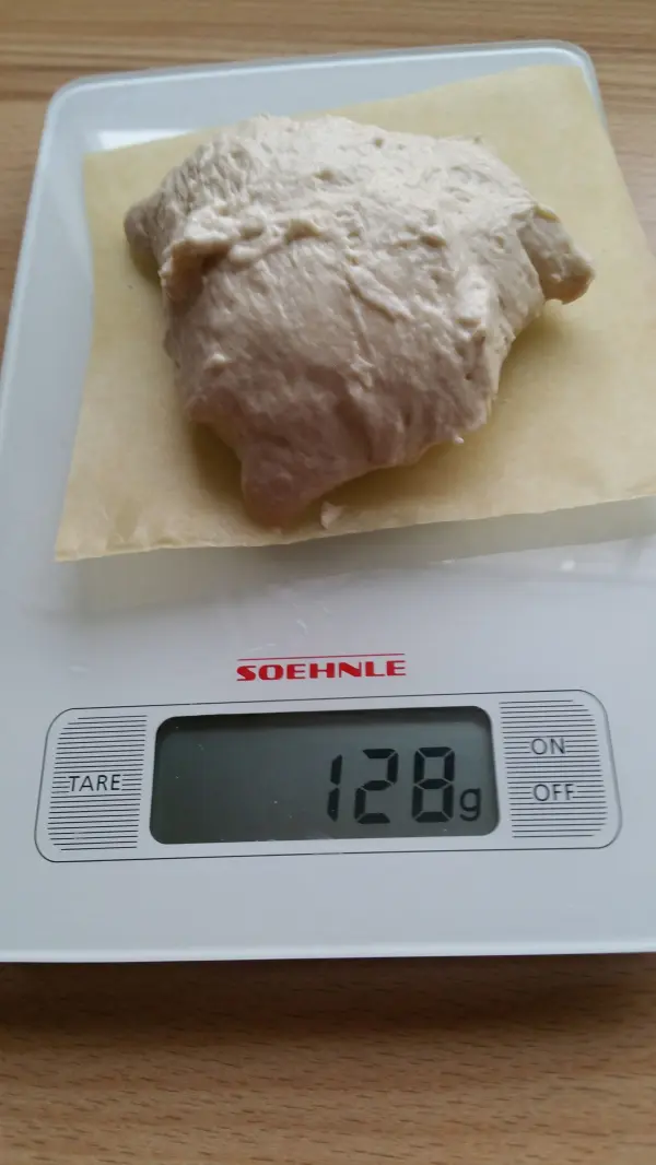 Ein Teigball liegt auf einer Küchenwaage und zeigt 128 g, bereit zur Zubereitung von schnellen Joghurtbrötchen.
