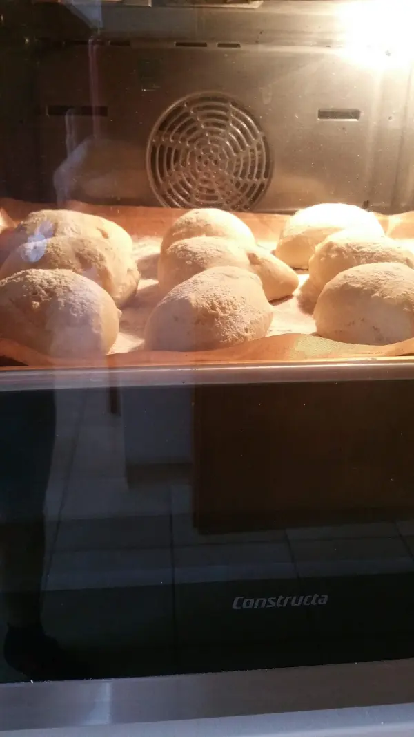 Im Ofen, auf einem Blech, liegen frisch geformte Joghurtbrötchen, die goldbraun backen.