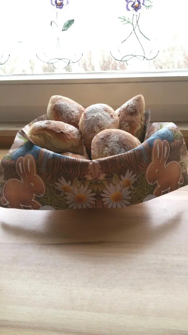 In einer dekorativen Schale liegen frisch gebackene Joghurtbrötchen, umgeben von einem hellen Küchenambiente.