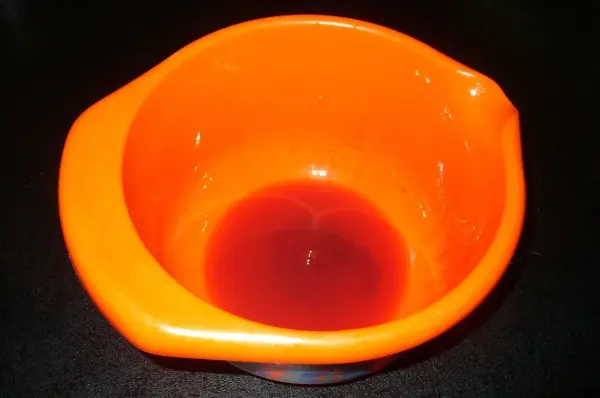 Eine orange Schüssel fängt den austretenden Saft von frischer Leber auf, während sie abtropft und darauf wartet, weiterverarbeitet zu werden.