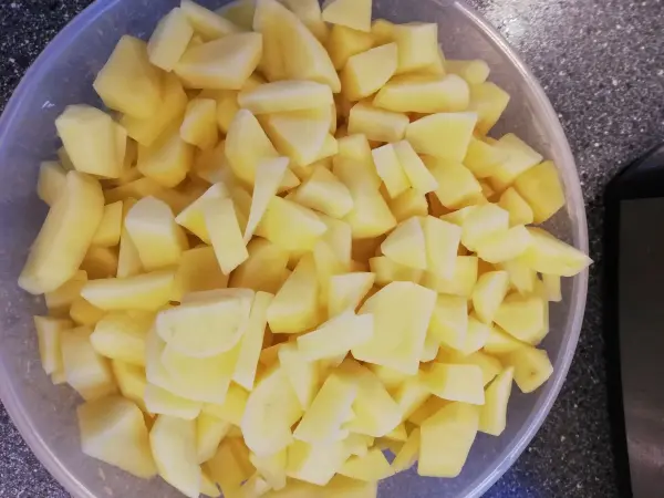 Stückige Äpfel liegen in einer Schüssel auf einer Arbeitsplatte, bereit für die Zubereitung des Bohneneintopfs.