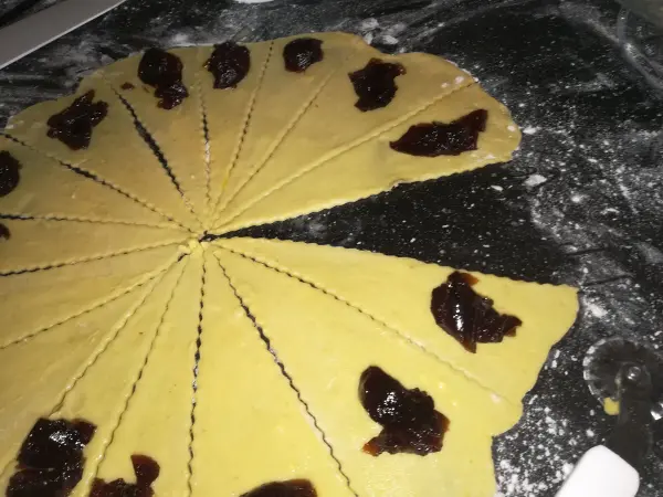 Teig für süße Schmalzkipferl ist in einem Kreis ausgerollt und mit Marmelade belegt, bereit zum Backen.