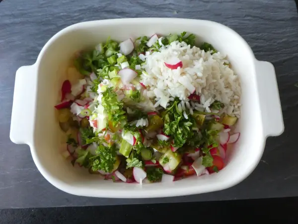 Eine Schüssel mit buntem Wurstsalat und frischem Gemüse ist auf einem dunklen Untergrund platziert, bereit zum Servieren.