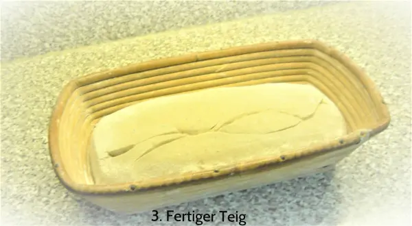 Ein Teig im Gärkörbchen ruht und bereitet sich auf das Backen von Sauerteig-Roggenmischbrot vor.