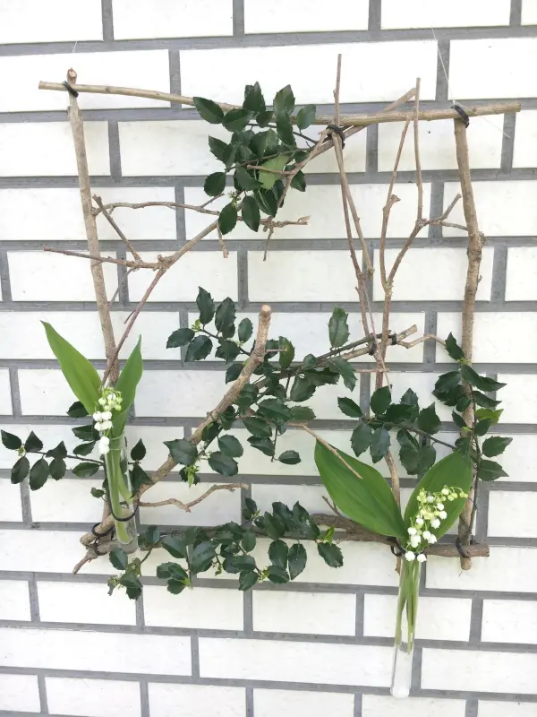 Ein schöner Fensterschmuck aus Zweigen und Blättern wird dekorativ an einer weißen Wand arrangiert.