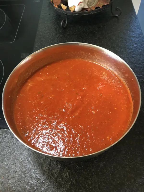 Eine große Schüssel mit frischem Tomatenbelag steht auf einer schwarzen Arbeitsfläche, bereit für die perfekte Pizza.