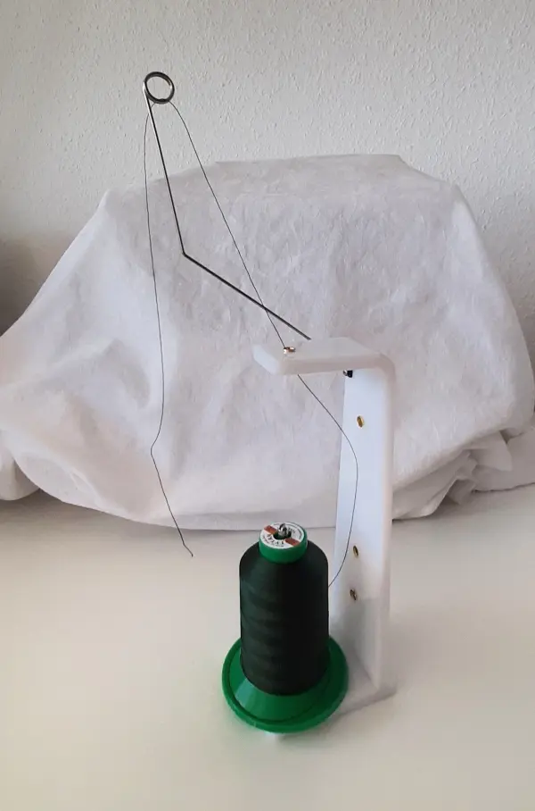 Ein Nähgerät steht auf einem Tisch und hält einen schwarzen Faden bereit, um Sonnenschutz und Windschutz zu entwerfen und zu nähen.