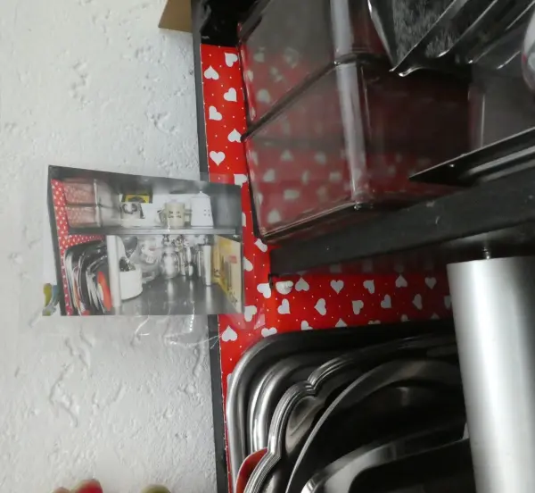 Auf einem Tisch liegen mehrere durchsichtige Aufbewahrungsboxen und Küchenutensilien, um Ordnung in Regalen zu halten.