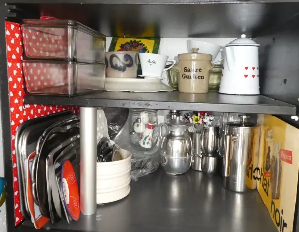 In einem Schrank sind verschiedene Küchengeräte und Geschirr ordentlich angeordnet, um Übersichtlichkeit zu erhalten.