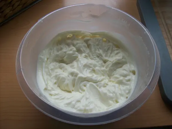 Ein cremiger Quark-Frischkäse in einer Schüssel, bereit für die Zubereitung eines Himbeer-Desserts auf einem Tisch.