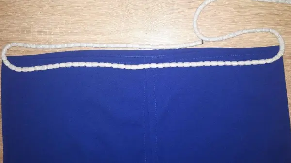 Ein blauer Bleistiftrock liegt flach auf einem Tisch, oben ist eine weiße Schnur zum Sichern des Rocks sichtbar.