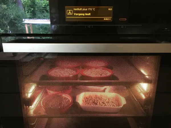 Im Ofen backen mehrere schwedische Blaubeer-Tartelettes, während die Wärme das Innere der Backform erleuchtet.