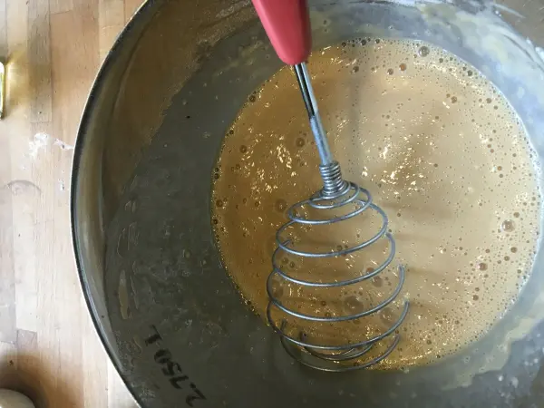 Eine Rührschüssel enthält eine Mischung für schwedische Blaubeer-Tartelettes, während ein Schneebesen für die Zubereitung verwendet wird.