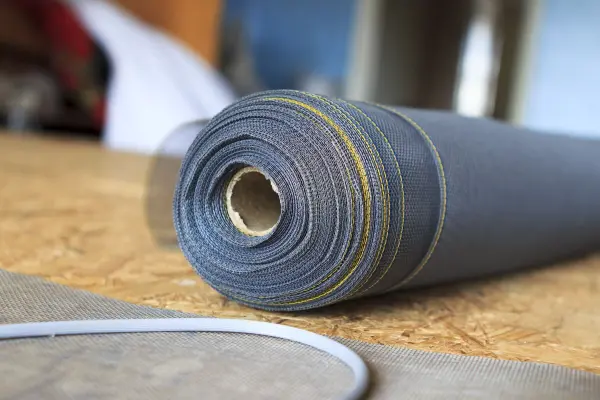 Ein Fliegennetz-Rollenmaterial liegt auf einem Tisch, bereit zum Öffnen und Schließen für eine Insektenabwehr.