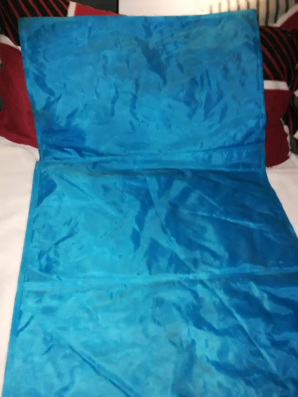 Eine Hundekühlmatte in leuchtendem Blau liegt flach auf einem Bett, um eine kühle Liegefläche für Haustiere zu bieten.