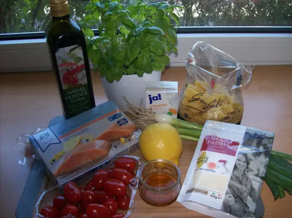Rigatoni und frische Zutaten liegen auf einem Tisch; Tomaten, Zitrone und Basilikum zu einem leckeren Pastarezept.