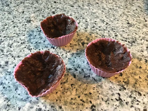 Schokoladenförmchen stehen auf einer marmorierten Arbeitsfläche, bereit für ein köstliches Erdbeerdessert.