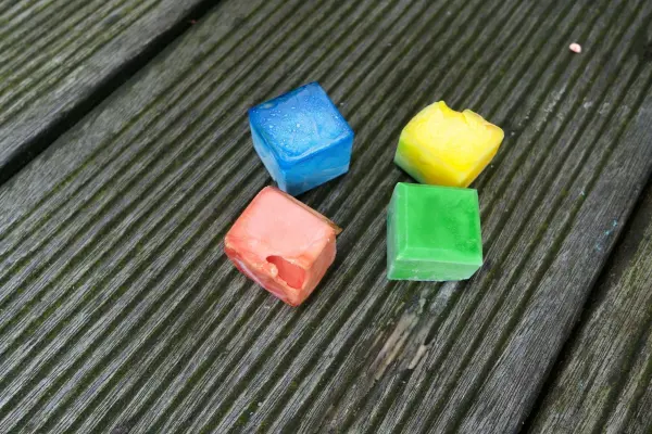 Bunte Eiskreidewürfel liegen auf einer Holzoberfläche und warten darauf, im Sommer verwendet zu werden.