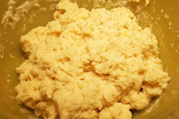 Eine knetbare Teigmischung für den Blechkuchen, die in einer großen Schüssel zusammengemischt wird, sieht darauf unordentlich aus.