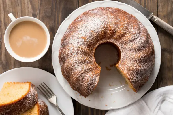 Ein saftiger Kuchen liegt auf einem weißen Teller, umgeben von einer Tasse Kaffee und einem Stück Kuchen.