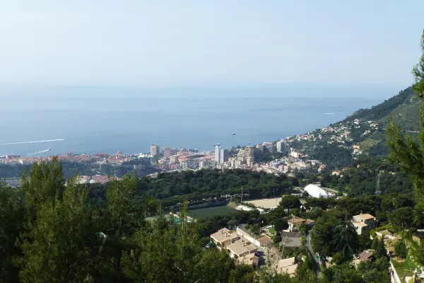 Eine malerische Küstenstadt liegt am Meer, umgeben von Bergen und grüner Vegetation, ideal für umweltfreundliches Reisen.