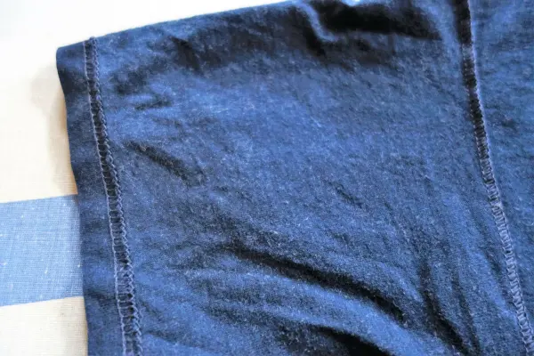 Ein blauer Stoff mit Fusseln liegt auf einer Tischfläche, während ein Staubsauger es gründlich reinigt.