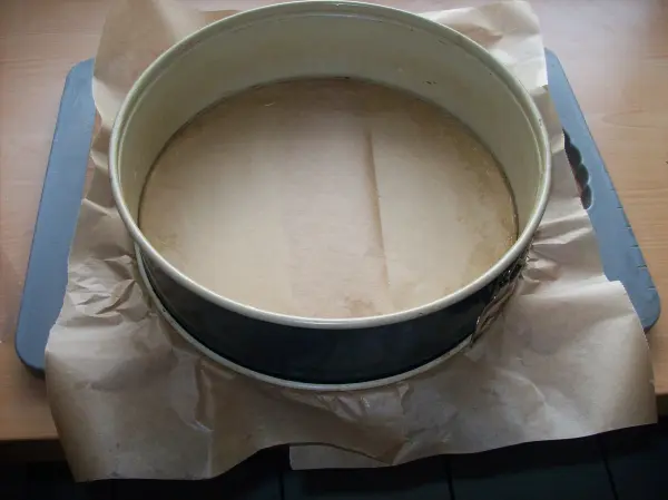 Ein runder Backrahmen steht auf einem Backblech, bereit für die Zubereitung eines perfekten Käsekuchens in einer hellen Küche.