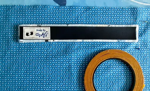 Ein gewebter Stoff in Blau mit weißem Punktmuster hat ein Etikett und Klebeband daneben, bereit zum Nähen eines Babynests.