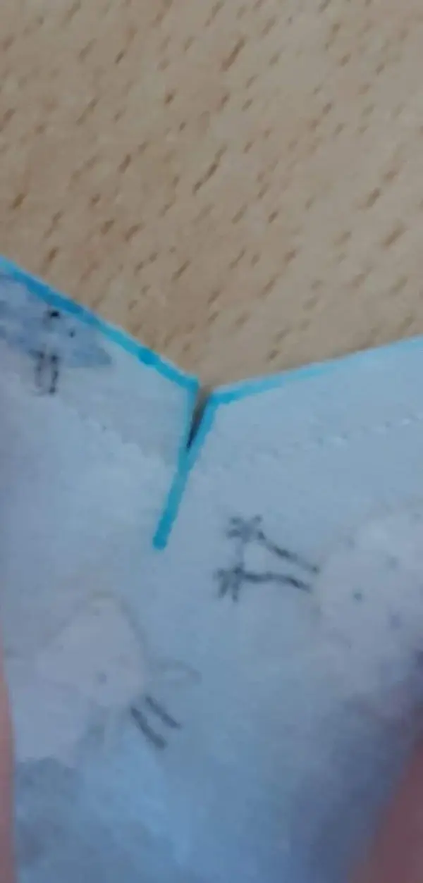 Ein Nähprojekt zeigt einen blauen Stoff mit einer gestrichenen Kante, während jemand das Babynest vorbereitet.