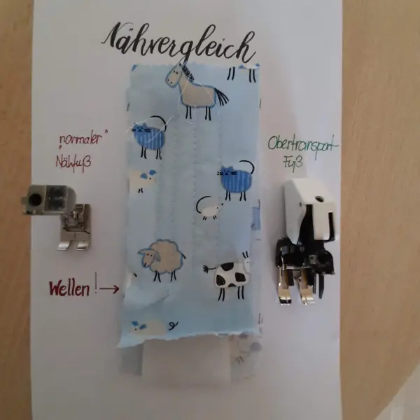 Ein Stoffstück mit Tiermotiven hängt an einer Wand, um verschiedene Nähfüße für das Babynest zu präsentieren.
