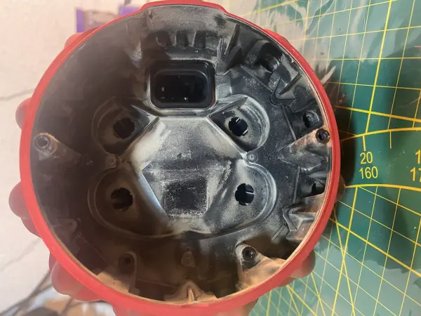Ein roter Boden eines Dyson Staubsaugers wird gezeigt, der mit Staub und Schmutz bedeckt ist; möglicherweise Ursache für den Geruch.