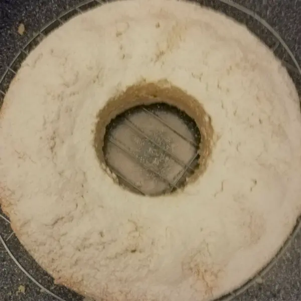 Ein Quark-Gugelhupf aus hellem Teig liegt auf einem Tisch, umgeben von Mehl und mit einer weichen, runden Form.